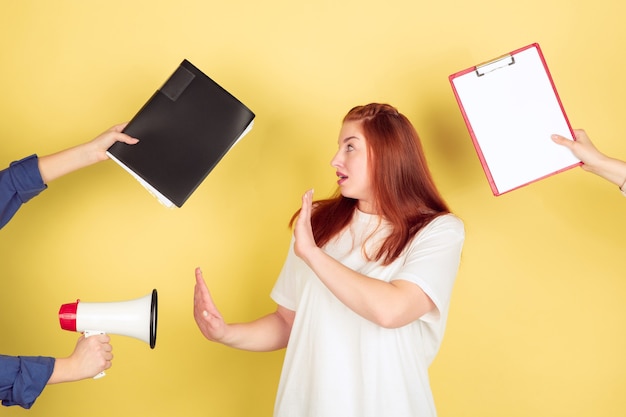 Sin informes. Retrato de mujer joven caucásica sobre fondo amarillo de estudio, demasiadas tareas. Cómo administrar el tiempo correctamente. Concepto de trabajo de oficina, negocios, finanzas, autónomo, autogestión, planificación.