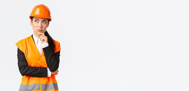 Ingeniera asiática creativa pensativa en casco de seguridad chaqueta reflectante mirando maíz superior izquierdo
