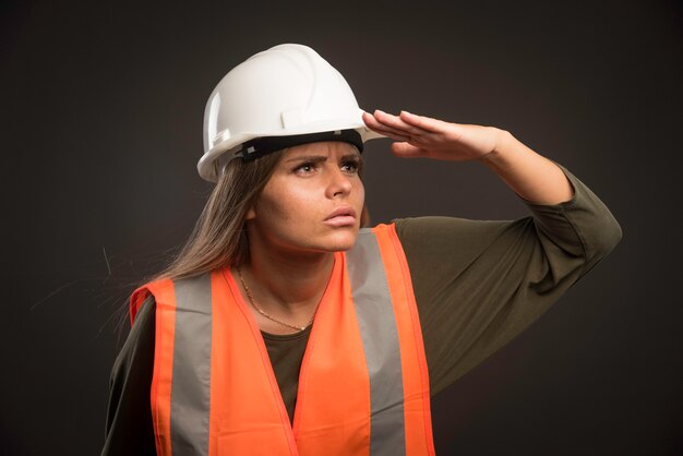 Ingeniera con un casco blanco y equipo y mirando hacia adelante.