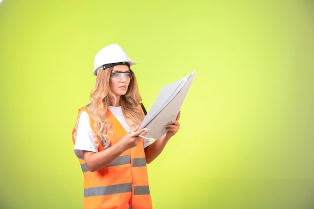 Foto gratuita ingeniera en casco y equipo sosteniendo el plan del proyecto y leyéndolo.