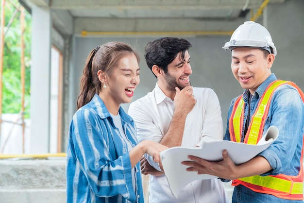 La ingeniera de inspección del sitio de felicidad y una clienta asiática se reúnen casualmente en el fondo de la ubicación de la estructura del sitio de renovación del hogar