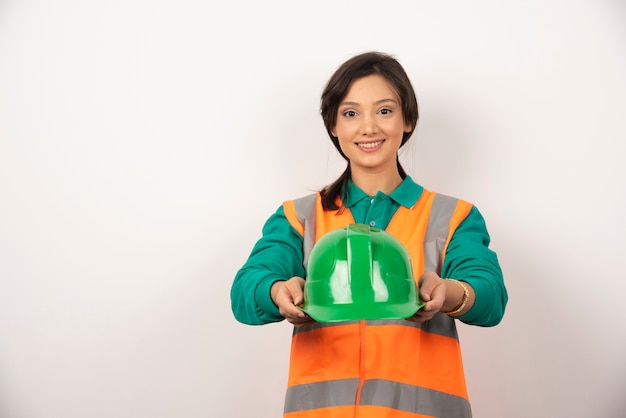 Foto gratuita ingeniera sonriente sosteniendo un casco sobre fondo blanco.