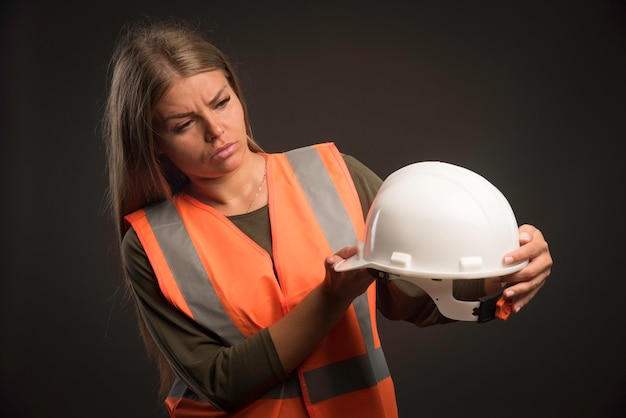 Ingeniera sosteniendo un casco blanco y parece serio.