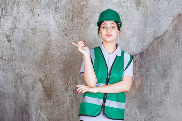 Ingeniera en uniforme verde y casco mostrando el lado izquierdo con emociones