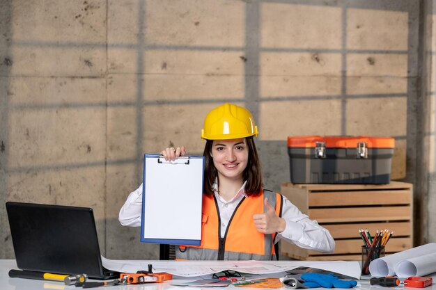 Ingeniero en casco y chaleco trabajador civil inteligente joven linda chica morena feliz