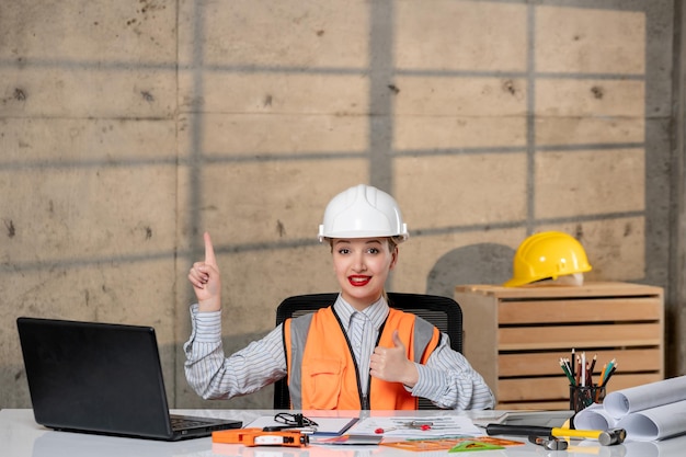 Ingeniero en casco y chaleco trabajador civil inteligente joven linda chica rubia muy emocionada