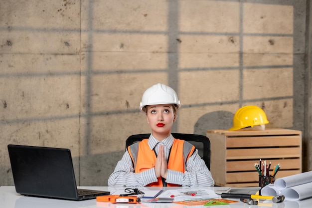 Ingeniero en casco y chaleco trabajador civil inteligente joven linda chica rubia rezando