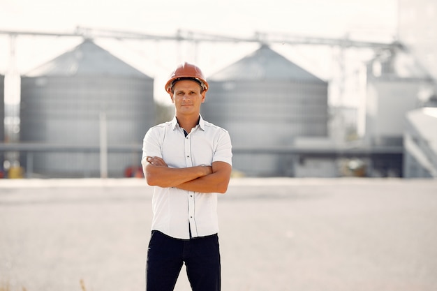 Ingeniero en un casco parado junto a la fábrica