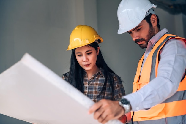 Ingeniero civil y gerente de trabajadores de la construcción con tableta digital y planos hablando y planeando sobre el sitio de construcción Concepto de trabajo en equipo de cooperación