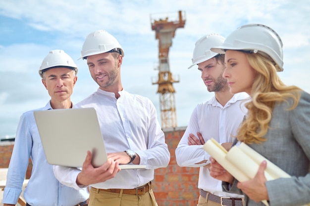 Foto gratuita ingeniero de construcción mostrando algo a sus colegas en su computadora portátil