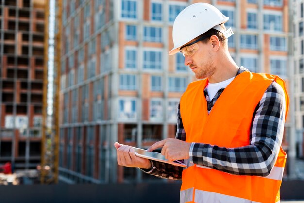 Ingeniero de construcción de la vista lateral del tiro medio que usa la tableta