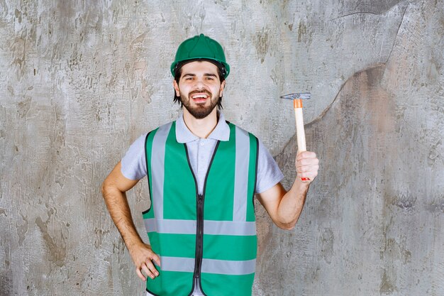 Ingeniero en engranaje amarillo y casco sosteniendo un hacha con mango de madera.