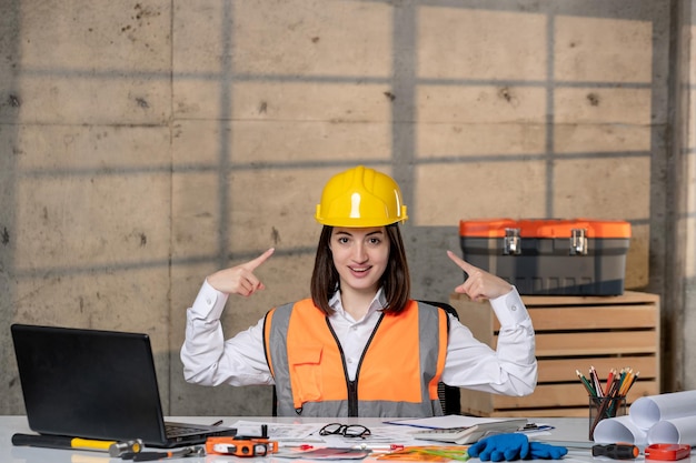 Ingeniero inteligente joven linda chica morena trabajador civil en casco y chaleco orgulloso