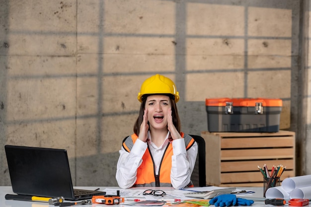 Ingeniero joven linda chica morena inteligente trabajador civil en casco y chaleco gritando