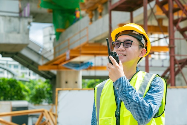 El ingeniero de lentes asiáticos inteligentes usa una conexión de radio que trabaja en la construcción del sitio