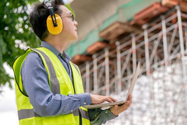 El ingeniero de lentes asiáticos inteligentes usa una conexión de radio que trabaja en la construcción del sitio