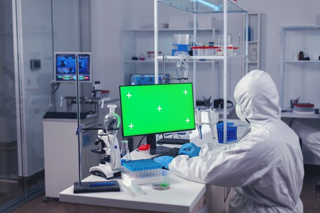 Ingeniero médico que realiza una investigación en una computadora con pantalla verde durante el covornavirus