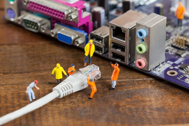 Ingeniero en miniatura y el trabajador plug-in de LAN por cable a la computadora