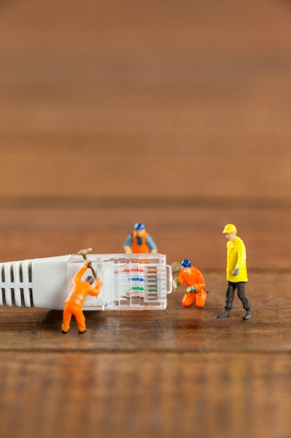 Ingeniero en miniatura y los trabajadores que utilizan cable LAN