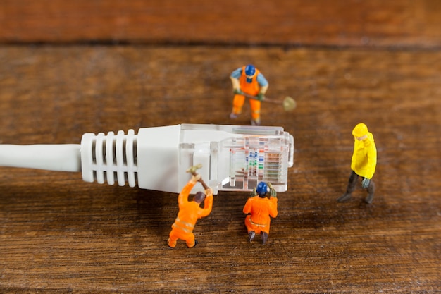 Ingeniero en miniatura y los trabajadores que utilizan cable LAN