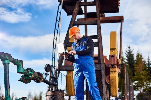 Ingeniero de petróleo usando laptop en campo petrolero