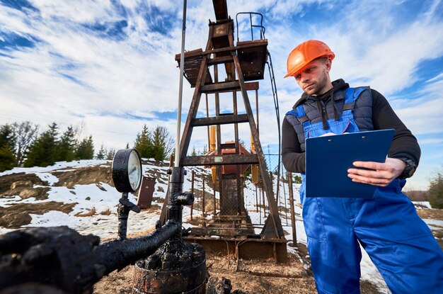 Ingeniero petrolero inspeccionando el gato de la bomba en el campo petrolero
