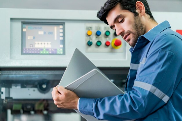 Ingeniero profesional caucásico masculino examina el progreso del sistema de maquinaria de control del flujo de trabajo y el resultado del proyecto en el concepto industrial y tecnológico de fondo de fábrica