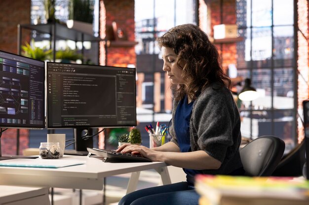 Ingeniero de software afroamericano trabaja en monitores duales y escritura de código