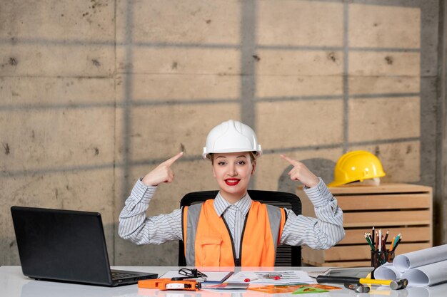 Ingeniero trabajador civil en casco y chaleco inteligente joven linda chica rubia muy orgullosa