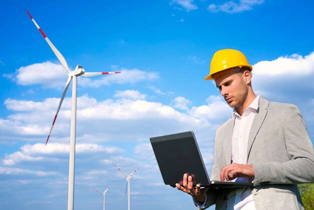 Ingeniero trabajando en su computadora portátil frente a generadores eólicos