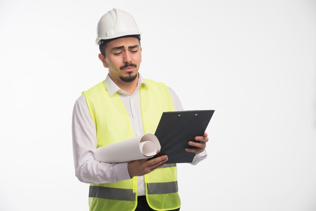 Ingeniero en uniforme revisando la lista de tareas y parece confundido.