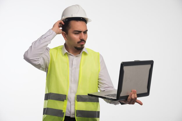 Ingeniero en uniforme sosteniendo una computadora portátil y reunión en línea.