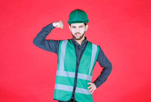 Ingeniero en uniforme verde y casco demostrando su puño.