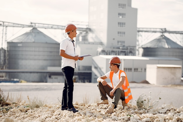 Ingenieros en cascos de pie junto a la fábrica.