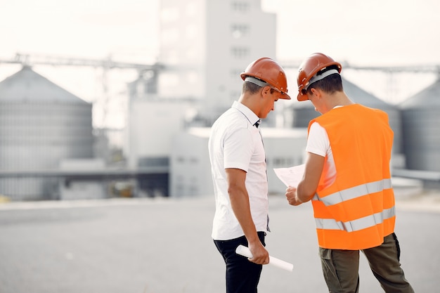 Ingenieros en cascos de pie junto a la fábrica.