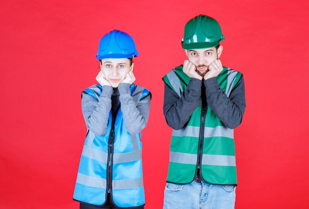 Los ingenieros masculinos y femeninos que usan casco y equipo parecen confundidos y pensativos.