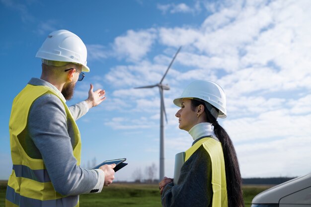 Ingenieros de tiro medio charlando sobre plantas de energía eólica.