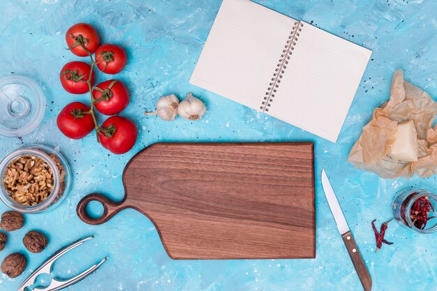 Ingrediente saludable y utensilio de cocina con diario abierto en blanco sobre fondo azul con textura