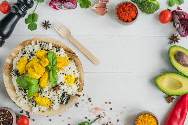 Ingredientes frescos y arroz frito en placa de madera con tenedor sobre mesa