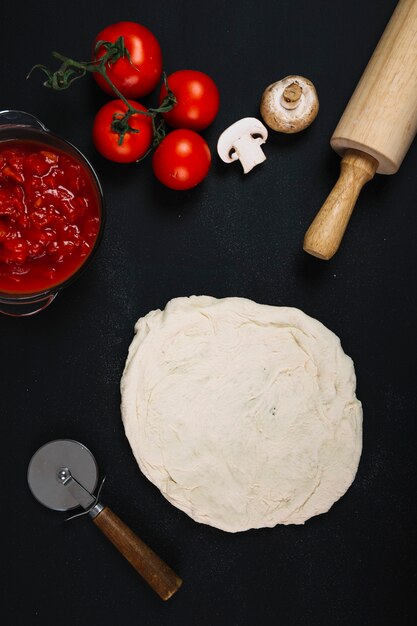 Ingredientes y utensilios cerca de la masa de pizza