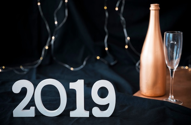 Foto gratuita inscripción 2019 con botella de champagne.