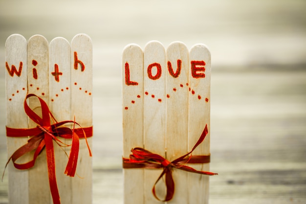 Foto gratuita inscripción de amor del día de san valentín en pequeños palos de madera con un corazón