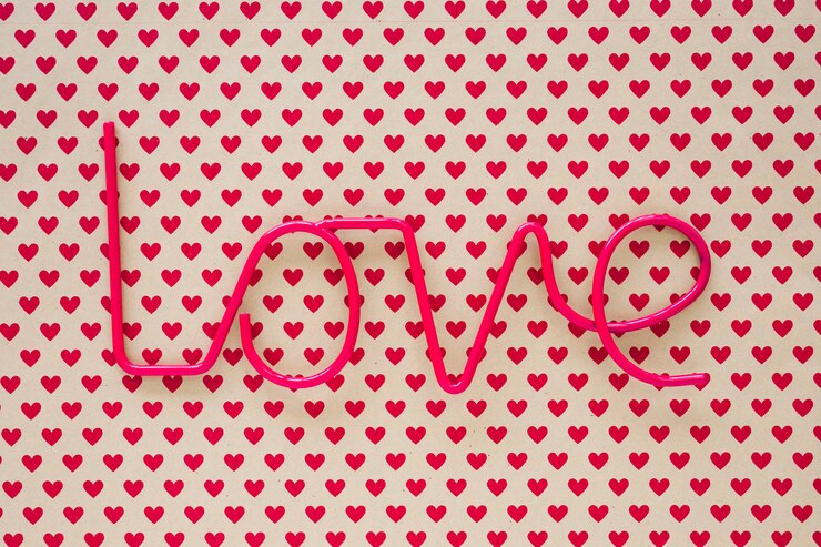 Foto gratuito inscripción de amor en mesa con patrón de corazón