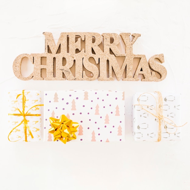 Inscripción decorativa feliz navidad cerca de cajas de regalo.