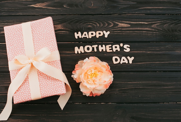Inscripción del día de la madre feliz con caja de regalo y flor