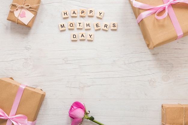 Inscripción del día de la madre feliz con caja de regalo y rosa