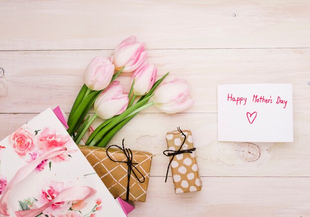 Inscripción del día de la madre feliz con tulipanes y regalos