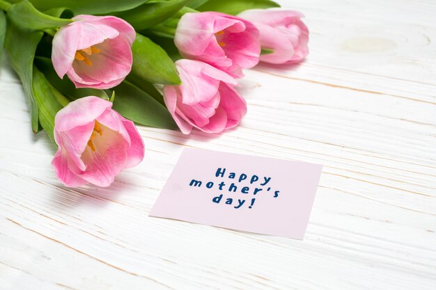Inscripción del día de la madre feliz con tulipanes rosa