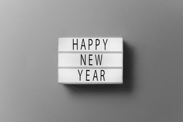 Inscripción de feliz año nuevo en el tablero blanco sobre mesa
