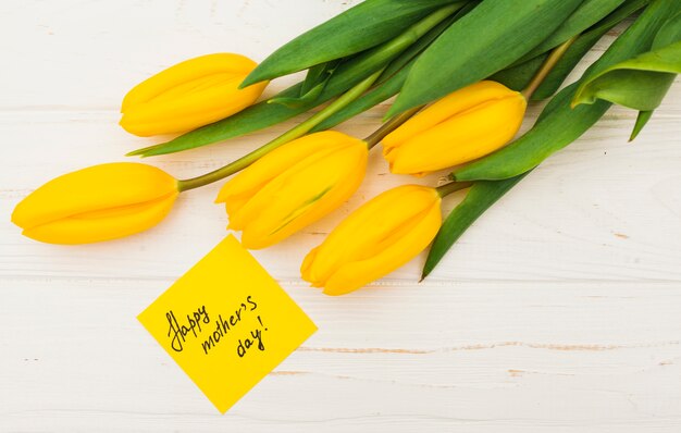 Inscripción de feliz día de las madres con tulipanes amarillos